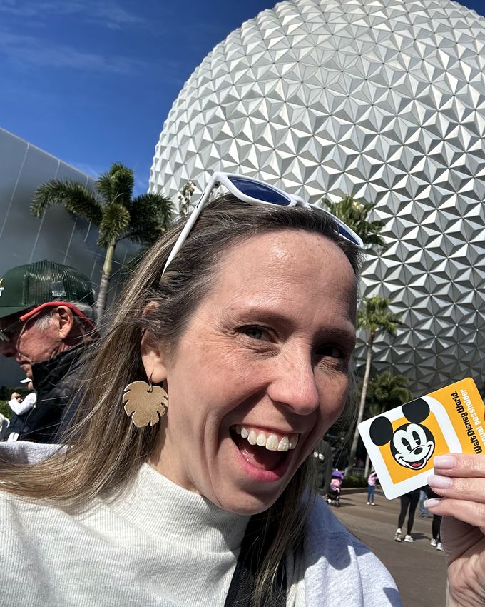 Lynne holding park tickets in front of Spaceship Earth